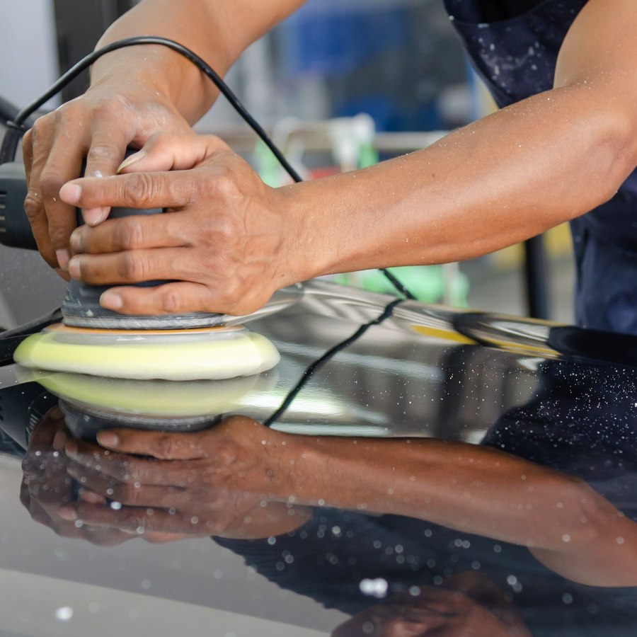 Detailer hand-polishing a car's hood